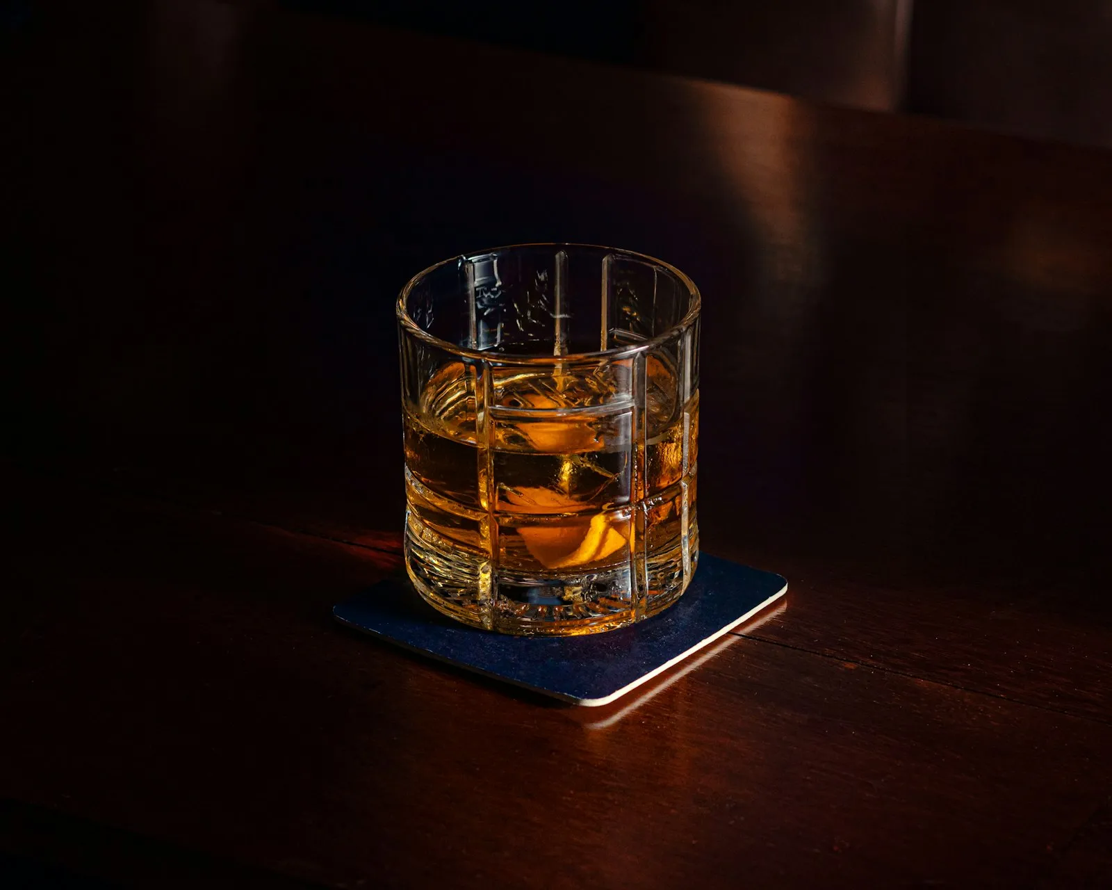 Et glass whisky på en ølbrikke på et mørkt trebord